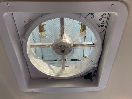 Close-up of an RV rental's ceiling vent fan with screen and controls. Maxxair vent provides essential airflow.