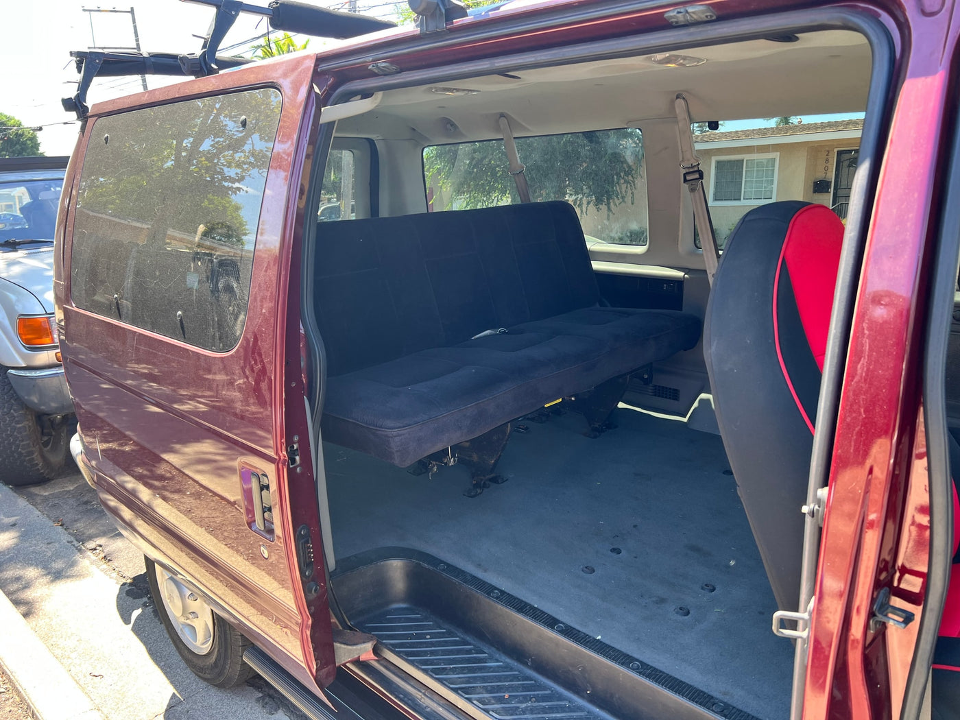Spacious maroon van interior with open side door, featuring a black convertible bench seat, ideal for rv rental adventures. — photo 3