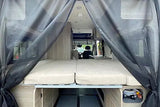 Spacious RV rental interior with a comfortable bed, under-bed storage, and a mesh screen at the rear entrance.