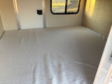 Interior of an RV rental: a large, light-colored quilted mattress creates a cozy sleeping area.