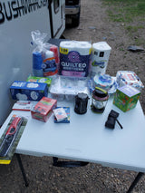 Preparing for an RV rental trip with essential camping supplies: cups, tissues, paper products, games, lanterns, and lighters.