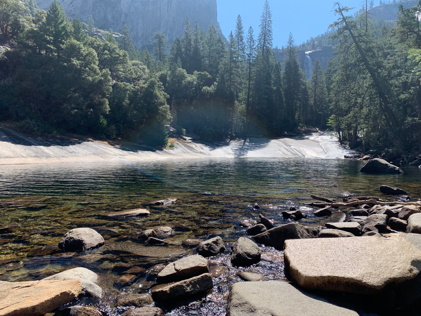 An RV rental brings you to stunning landscapes: clear river, majestic granite cliffs, and a distant waterfall.