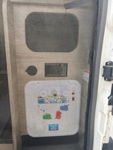 RV rental utility panel with water connections, valves, and controls visible behind a protective mesh screen.