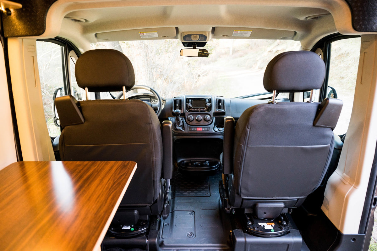 Inside an RV rental camper van: view of the driver's cabin from the living area, showing swivel seats, dashboard, and table. — photo 20