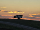 An off-road camper trailer, silhouetted on a hill against a fiery sunset with vibrant clouds. Your ideal rv rental for camping.