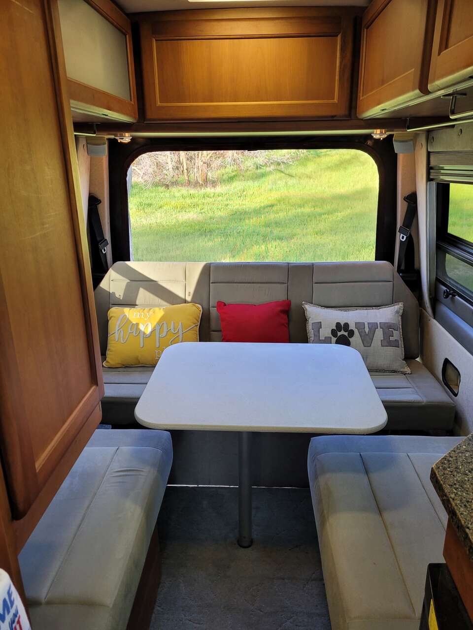  amidst desert trees and red rock formations.|Cozy rv rental dinette setup with soft seating — photo 2