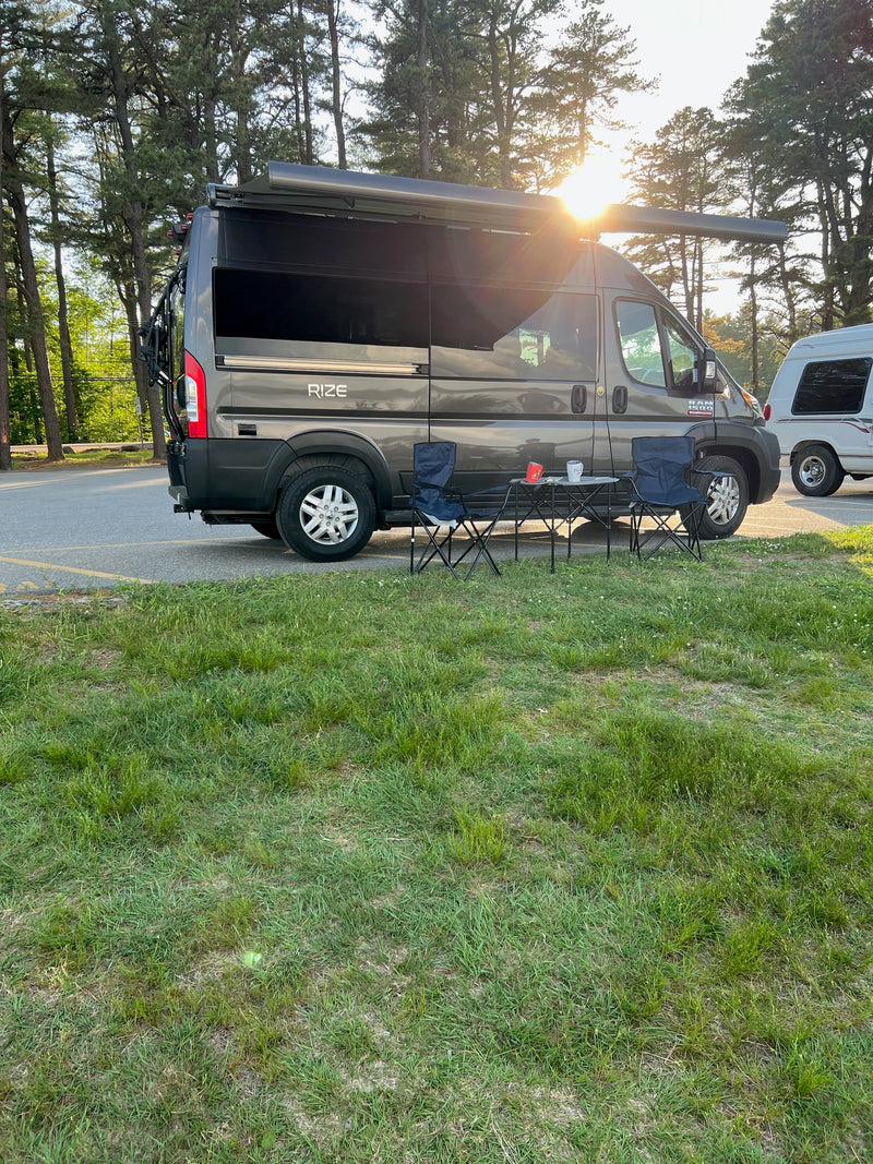 Rize RV rental camper van parked at a sunny campsite with chairs & table. Ideal for outdoor living and travel. — photo 5