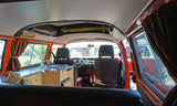 Inside a classic orange camper van, featuring a compact kitchen, front seats, and curtains. Ideal RV rental for trips.
