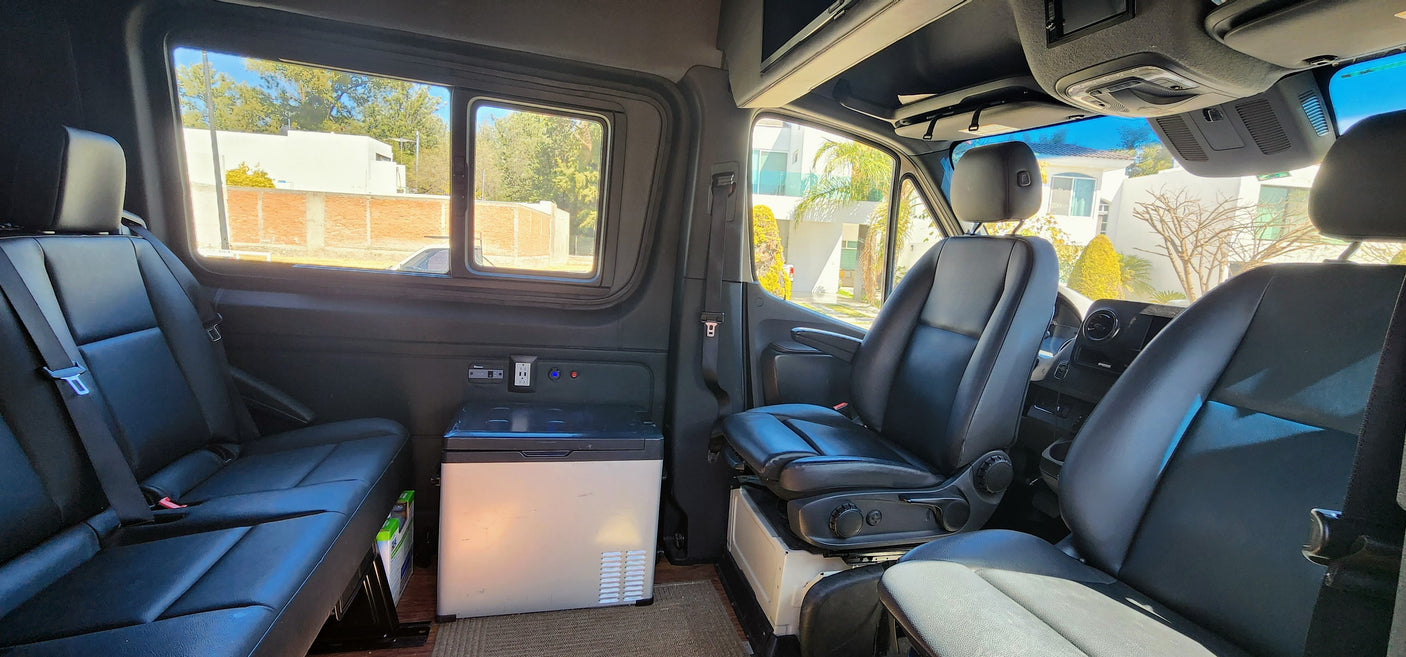 This RV rental's spacious van interior features comfortable seating, a portable fridge, and power outlets for your journey.