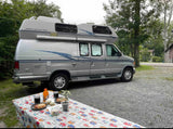 A silver Airstream 190 RV rental at a campsite with a picnic table set for a meal. Ideal for outdoor adventures and travel.
