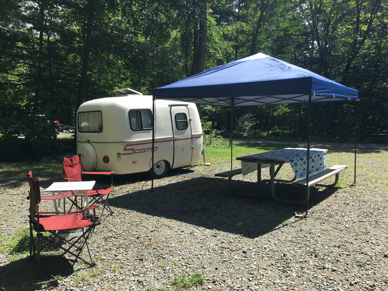 RV rental: Scamp trailer set up at a shaded campsite with a picnic area and chairs. — photo 3