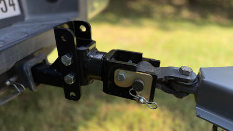 RV rental towing connection: Close-up of a black metal trailer hitch assembly, secured with bolts and a safety pin.