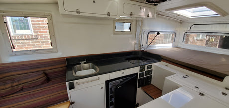 Experience our RV rental: a bright camper interior with a compact kitchen, comfy bed, and cozy seating.