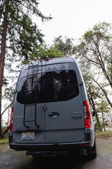 Rear view of a gray Mercedes Sprinter camper van with ladder & "VanCraft Campervans" logo, perfect for RV rental.