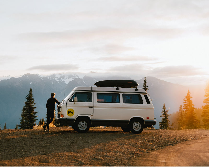 RV rental adventure: White camper van and person by snow-capped mountains at sunset — photo 1