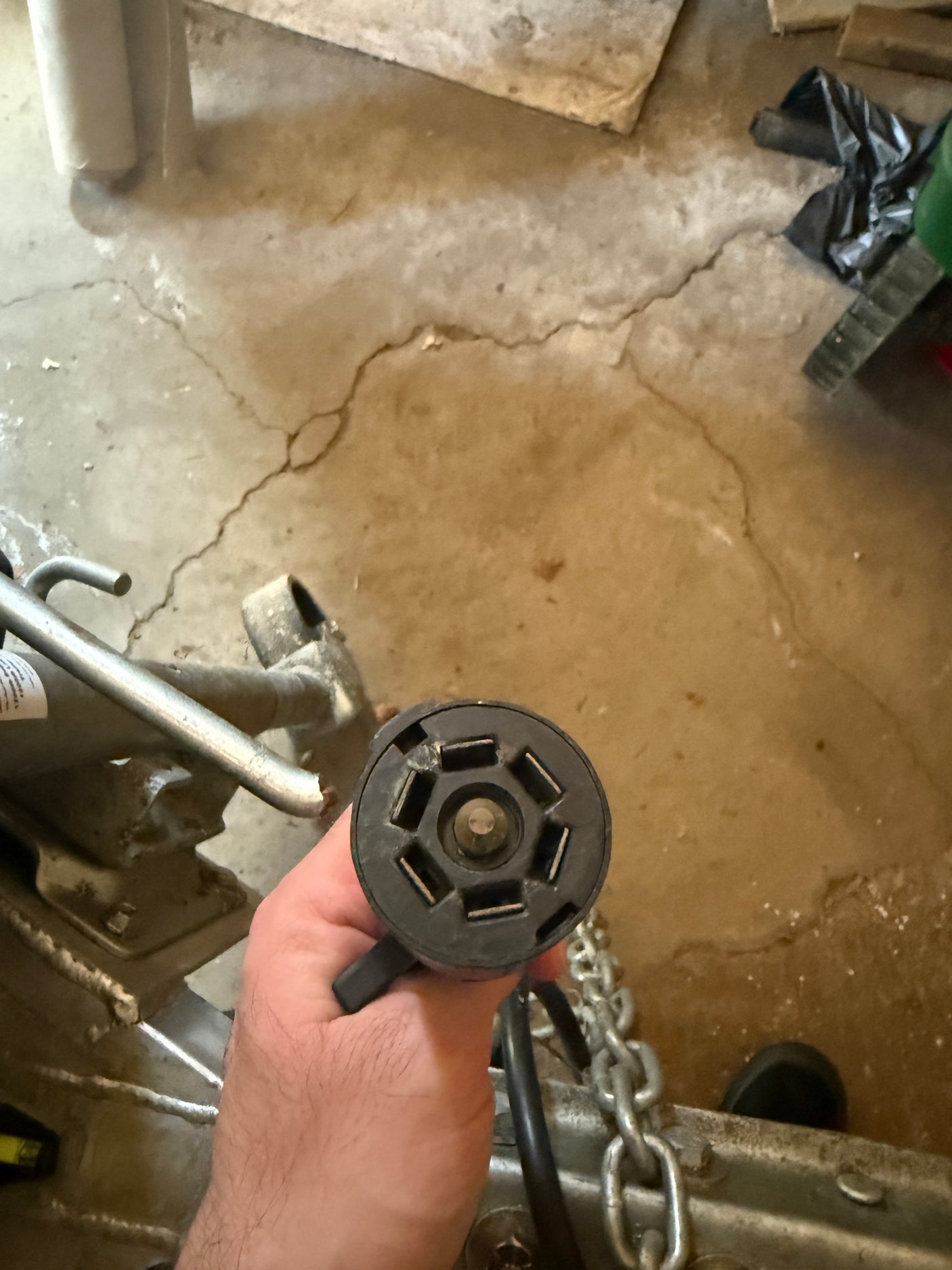 A hand holds a 7-pin round trailer electrical connector, crucial for RV rental hookup, powering lights and brakes.