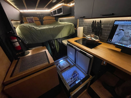 Inside this RV rental: raised bed, modern kitchen with fridge/freezer, cooktop, and storage for your adventures.