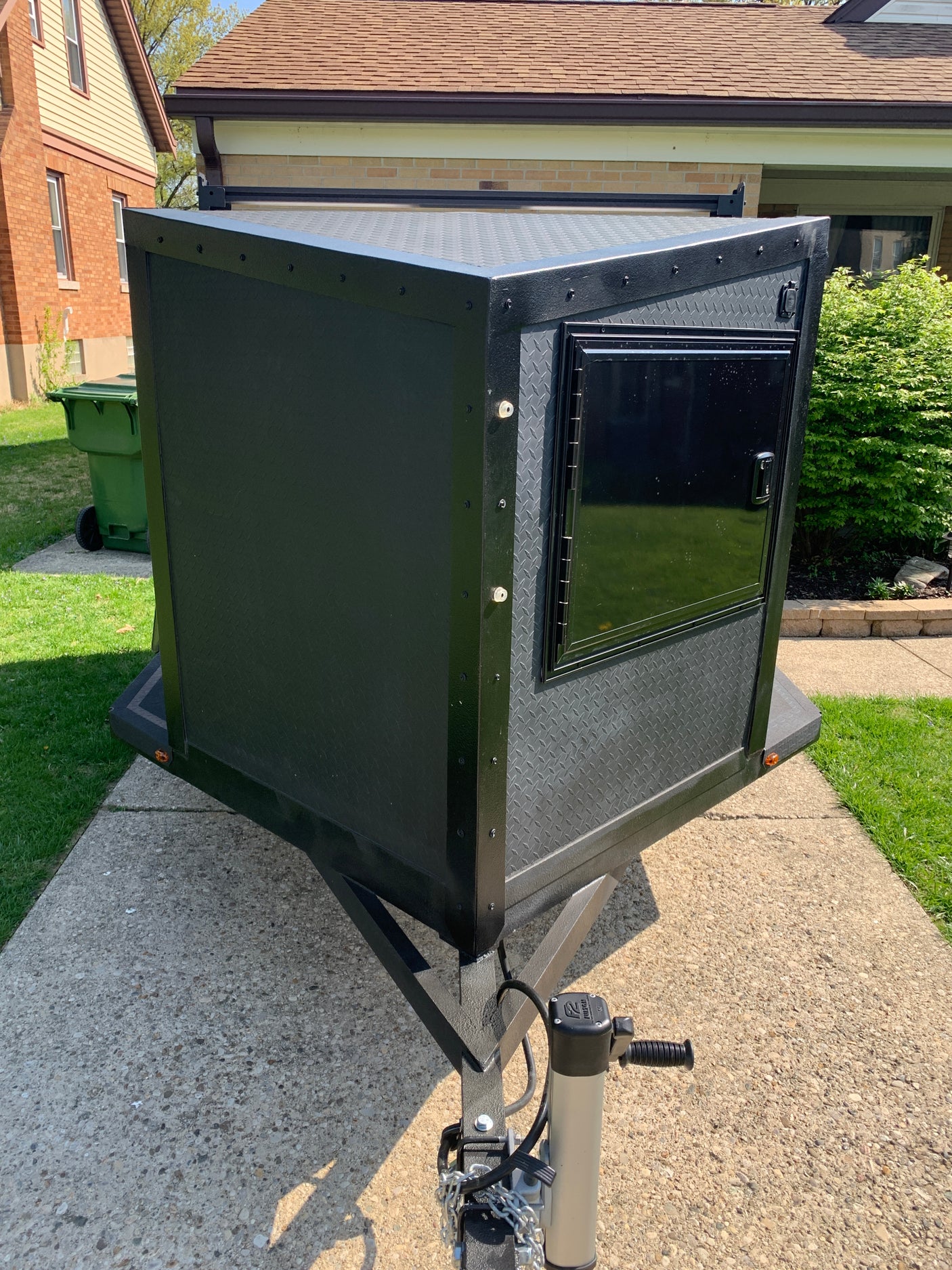 Rugged black utility trailer with diamond plate, ideal for gear on your next RV rental journey. Includes a side door.
