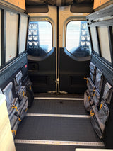 Rear cargo area of an RV rental, featuring modular wall storage bags & L-track flooring for organized gear.