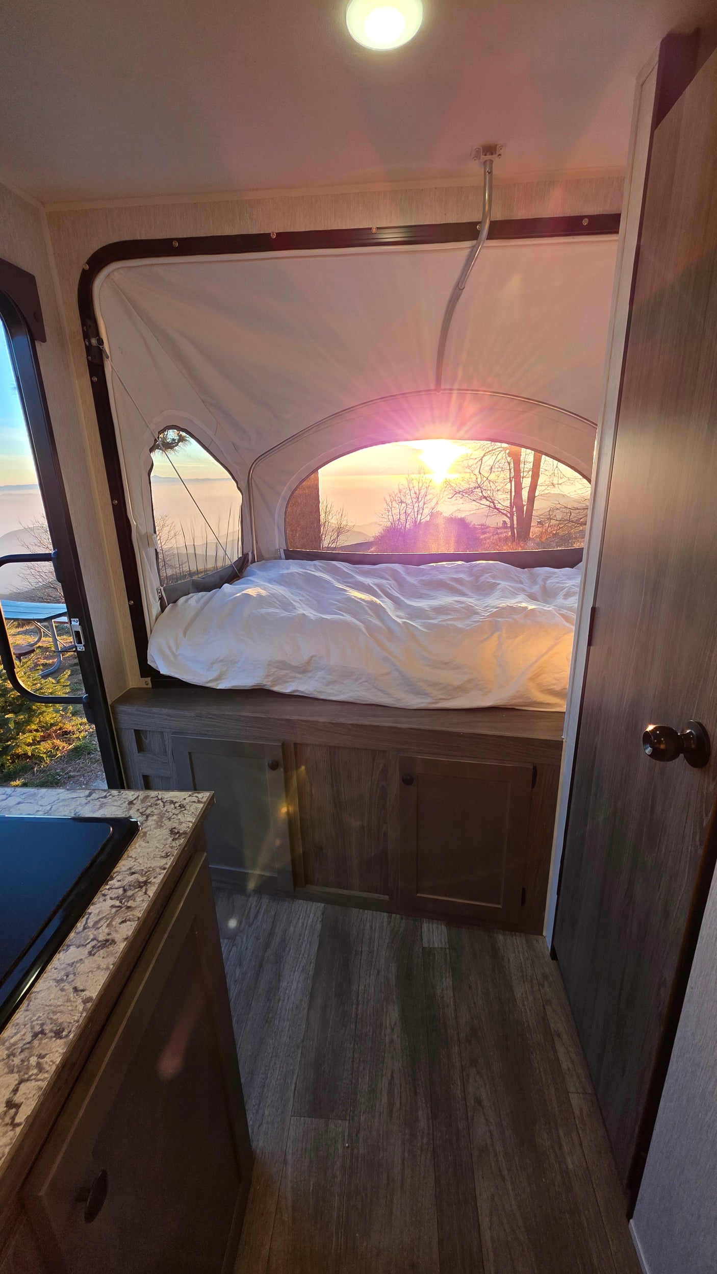 Cozy RV rental bedroom with a stunning sunrise view from the pop-out bed. Perfect for glamping in nature.