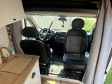 RV rental van interior: kitchenette with gold faucet, sink, and front cabin view with steering wheel and security bar.