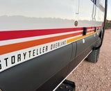 Storyteller Overland RV rental. Side view of white adventure van with stripes & rugged tires on gravel.