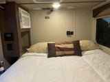 Cozy RV rental bedroom featuring a comfortable bed, wall-mounted AC unit, and TV backer location for travel.