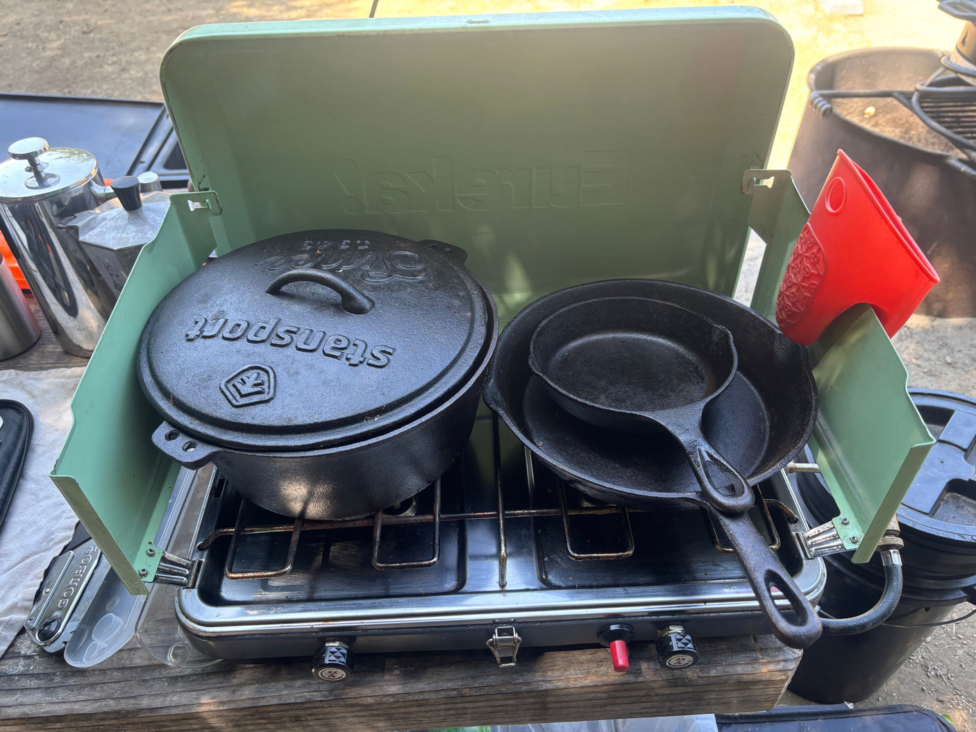 RV rental cooking: Eureka! camp stove with Woodsport cast iron Dutch oven & skillets ready for meals outdoors.