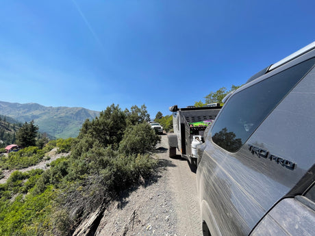  offers off-road overlanding at a forest campsite.|Explore off-road trails with a Toyota 4Runner towing an overland trailer. Consider this setup for an RV rental adventure!|Dusty Toyota 4Runner TRD Pro towing an off-road RV rental trailer on a scenic mountain dirt trail.|Campsite in a forest with an SUV
