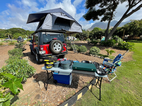 RV rental ready: Red Jeep with Thule Tepui rooftop tent & cooking gear for a perfect scenic campsite.