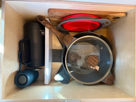 Organized RV rental drawer: compact cooking pan, portable blender, speaker, colander, and cutting board.