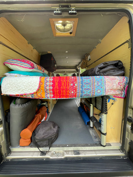 RV rental ready for adventure: custom van conversion with a colorful raised bed & ample under-bed storage.