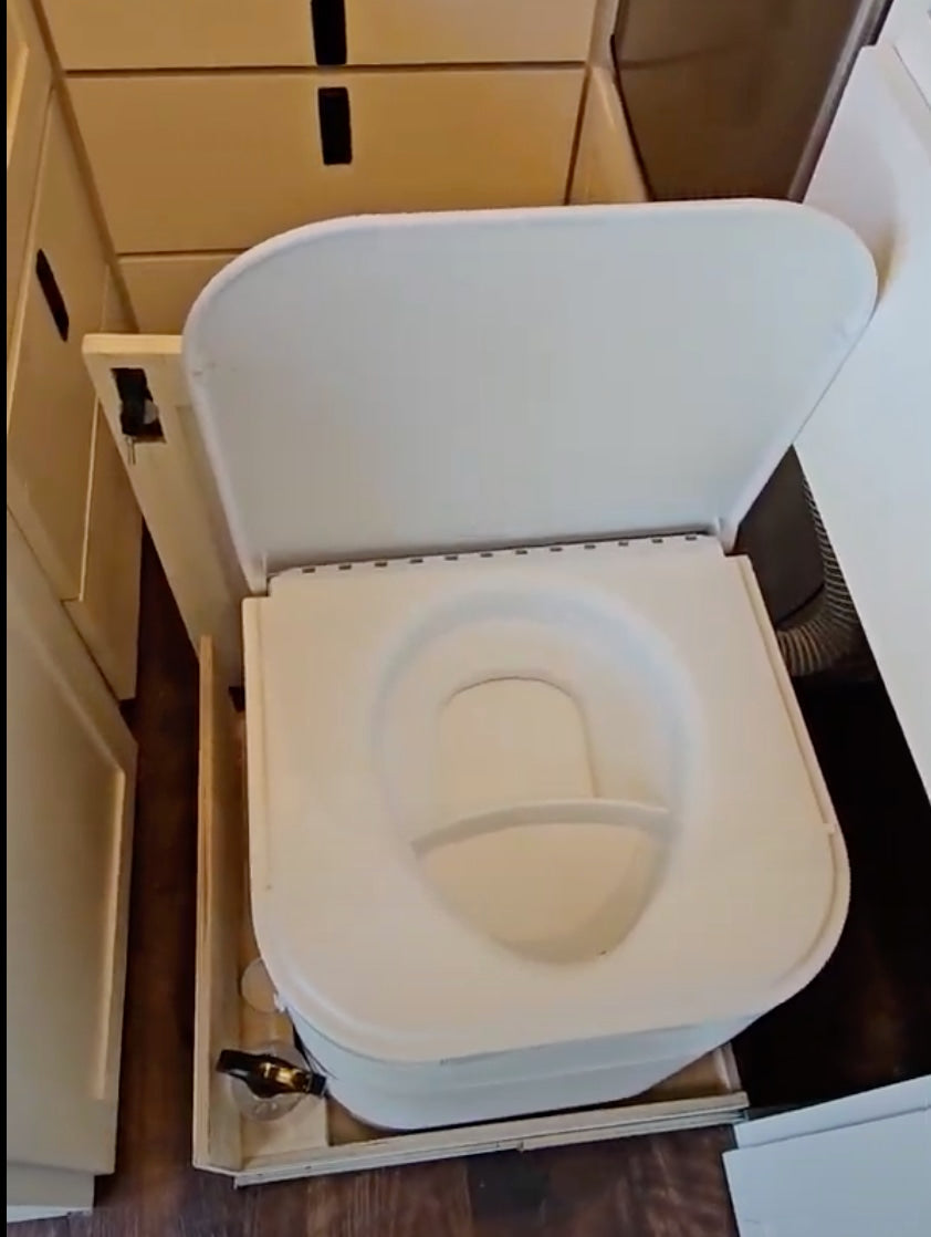 Compact composting toilet on a slide-out tray for an RV rental. Smart space-saving design in a mobile living space.