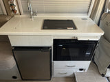 RV rental kitchen with a bright countertop, sink, Dometic cooktop, Nova Kool fridge, and High Pointe microwave, ideal for travel cooking.