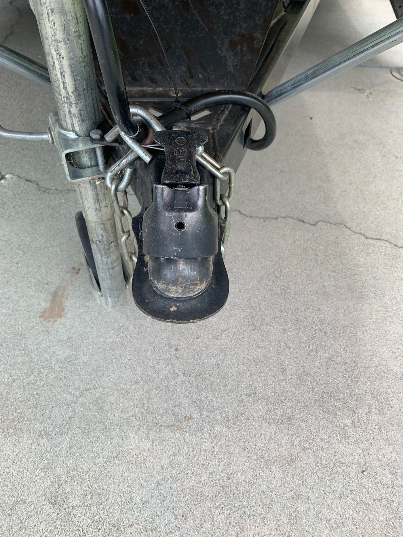 RV rental trailer hitch coupler and safety chains, connected to the A-frame on concrete. — photo 10