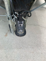 RV rental trailer hitch coupler and safety chains, connected to the A-frame on concrete.