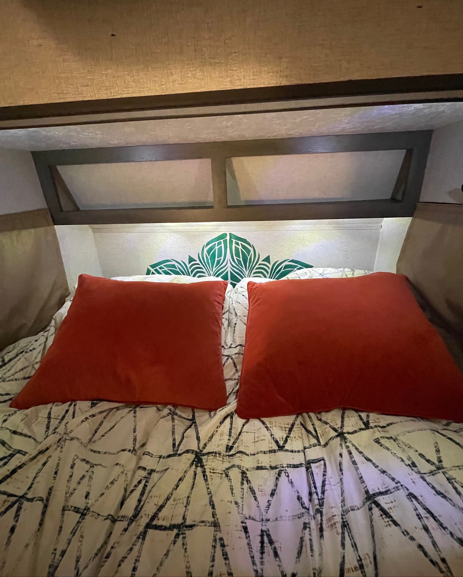 RV rental bedroom features: rust pillows, patterned bedding, and a green leaf-patterned headboard.