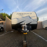 Front view of a Freesolo travel trailer, ideal for your next RV rental adventure, parked on a gravel lot under a clear sky.