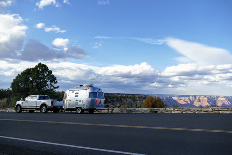 A Ford truck tows an Airstream RV rental at a scenic Grand Canyon overlook, perfect for an outdoor adventure.