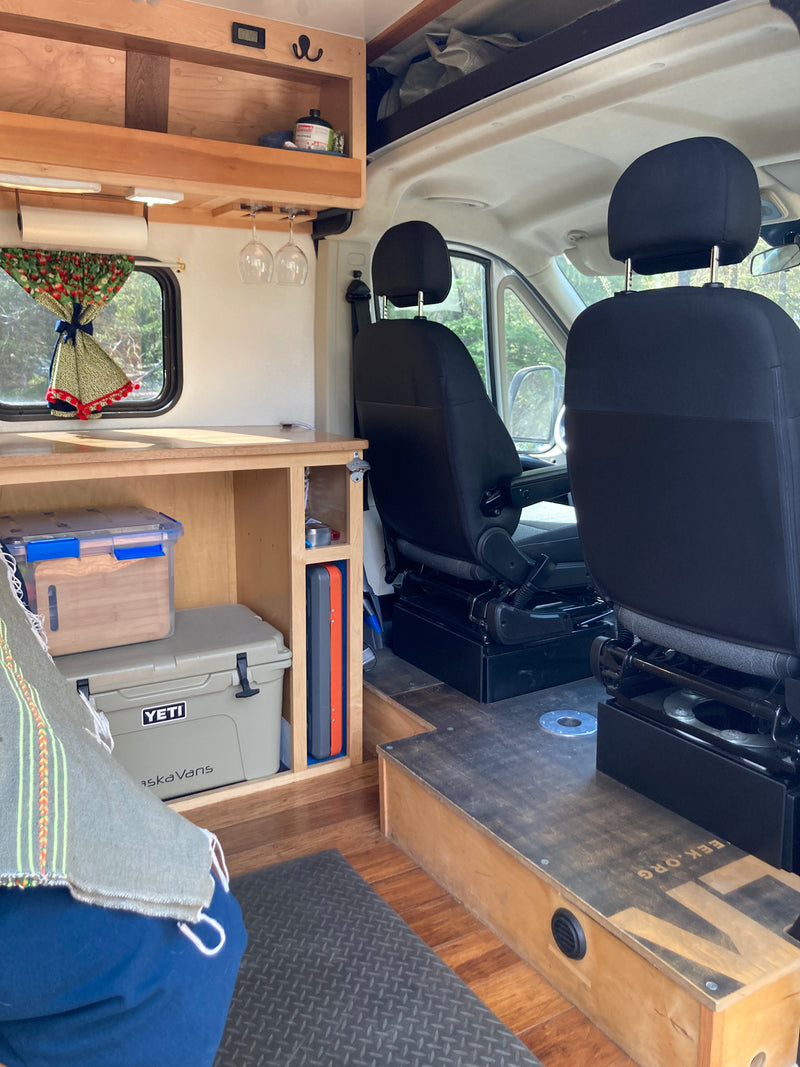 Custom RV rental interior features wood cabinetry, kitchen area, cooler, and swivel seats for comfortable travel. — photo 8