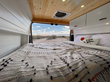 Enjoy serene desert views from this cozy camper van bed. Perfect for your next RV rental adventure.