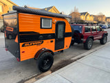 Orange Sunray Sport teardrop trailer, great for rv rental, hitched to a red off-road SUV. Ready for adventure!