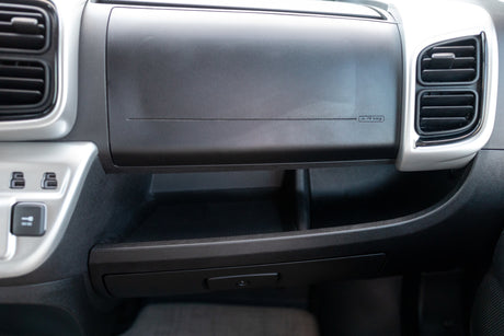 Passenger dashboard of an RV rental, featuring air vents, an 'AIR bag' glove box, and convenient multi-level storage with power outlets.