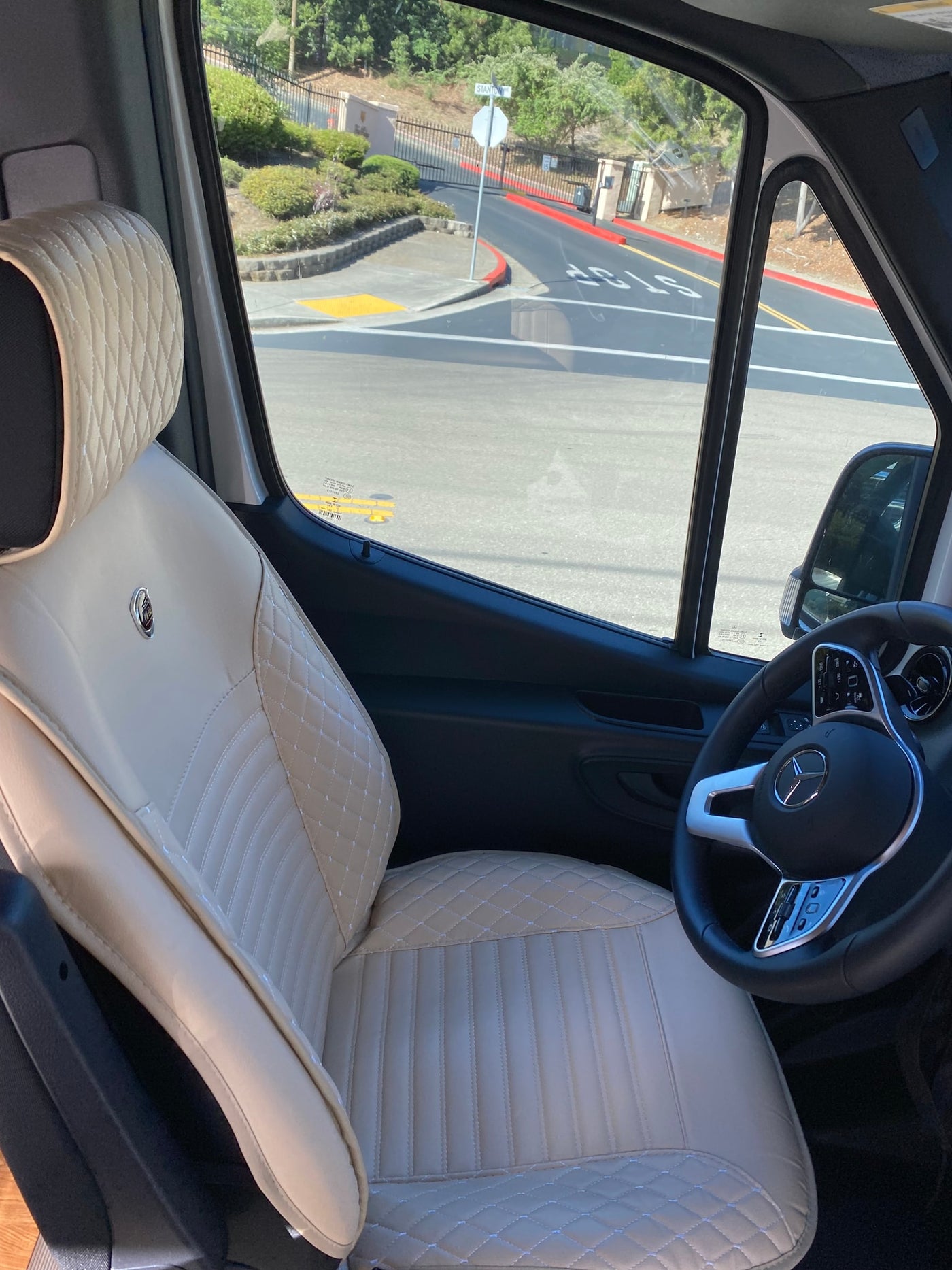 Inside an RV rental: luxurious cream quilted driver's seat and Mercedes-Benz steering wheel, with street view visible. — photo 2