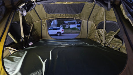 Cozy tent interior with mattress, looking out at an SUV. Ideal for your next rv rental adventure.
