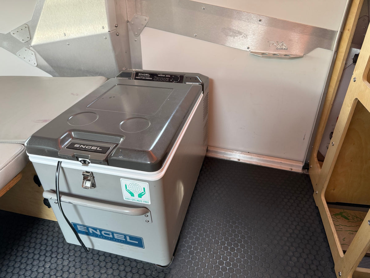 Engel portable fridge/freezer on a textured floor inside an RV rental, with metallic walls & wooden storage. — photo 7