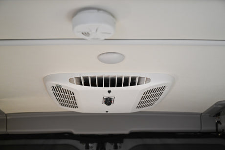 RV rental ceiling: A white AC unit, round light, and smoke detector are visible in the vehicle's interior.