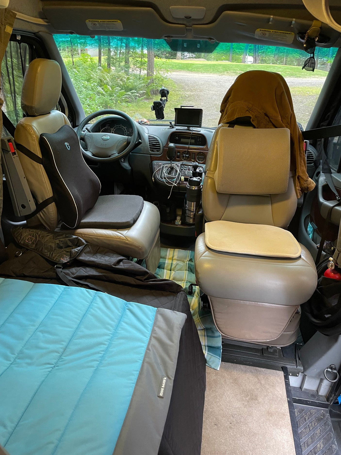 Front interior of a cozy rv rental camper van. Cushioned cockpit, dashboard area, & scenic view hint at adventure ahead.