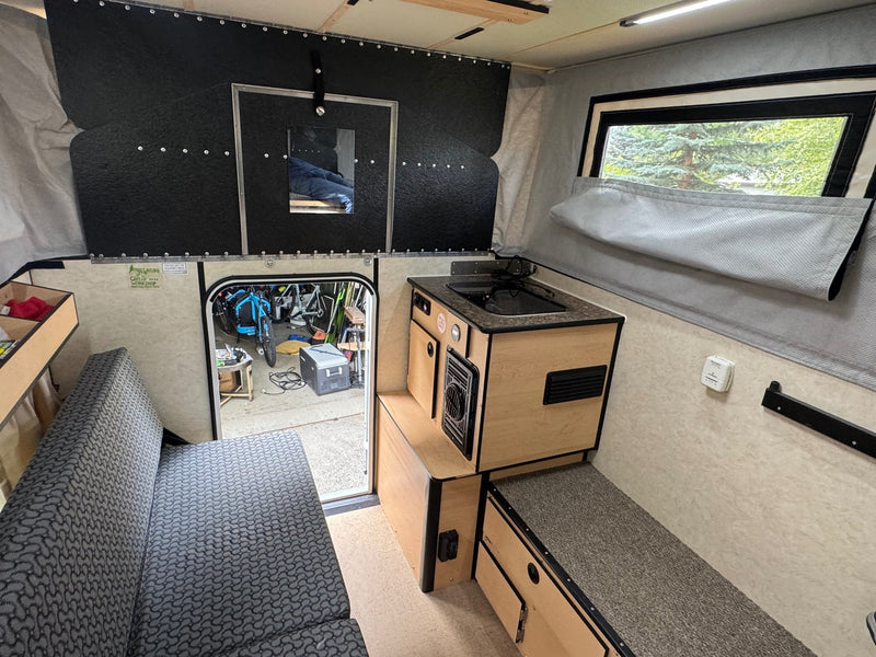  parked under trees.|White pop-up truck camper (Fleet) with raised roof & open door — photo 9
