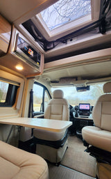 This inviting RV rental interior showcases a flexible dining area, overhead microwave, and a bright skylight.